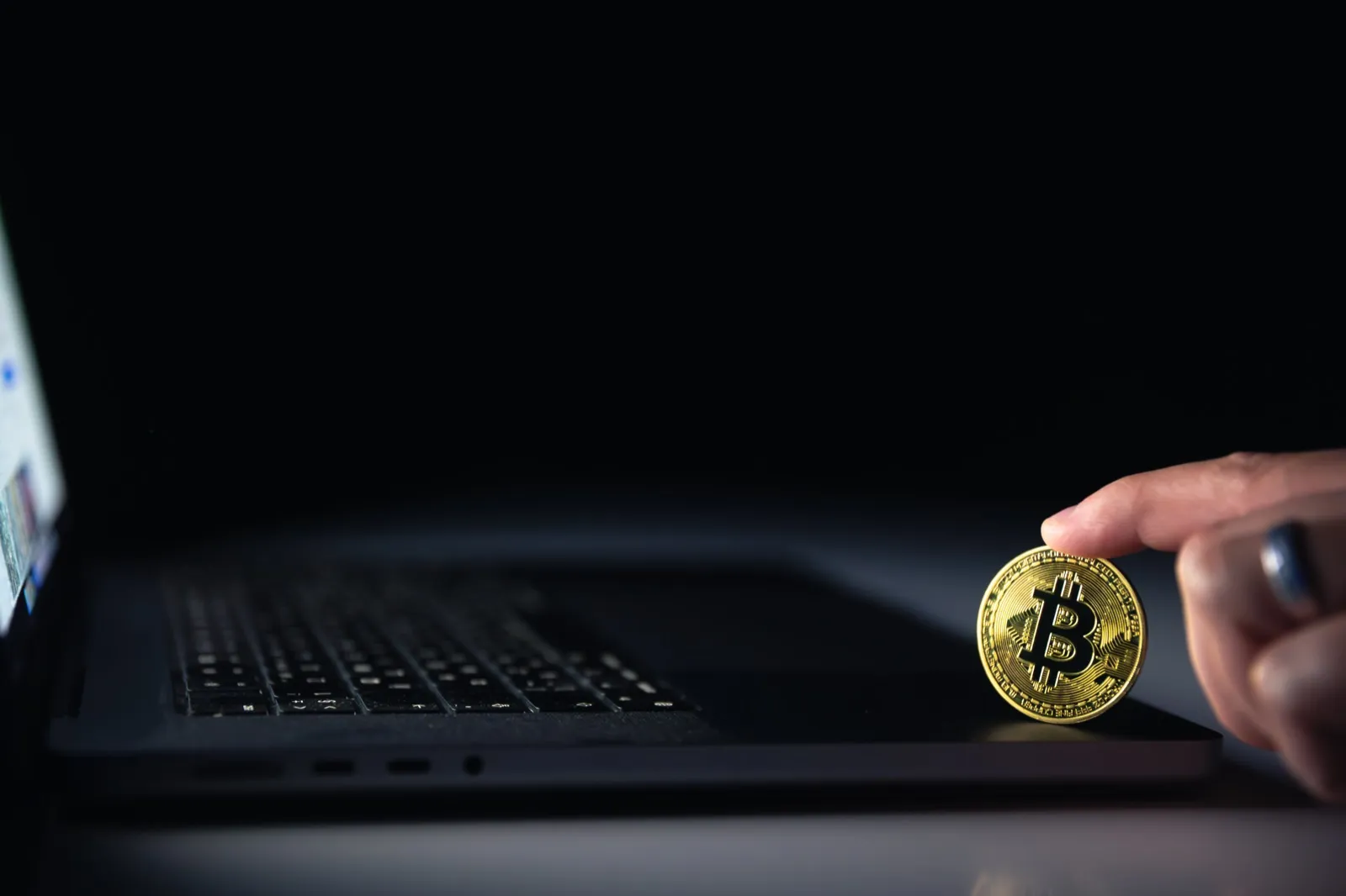 Moneta bitcoin przy laptopie - kontrola transakcji kryptowalutowych, Travel Rule i sankcji w giełdzie lub kantorze