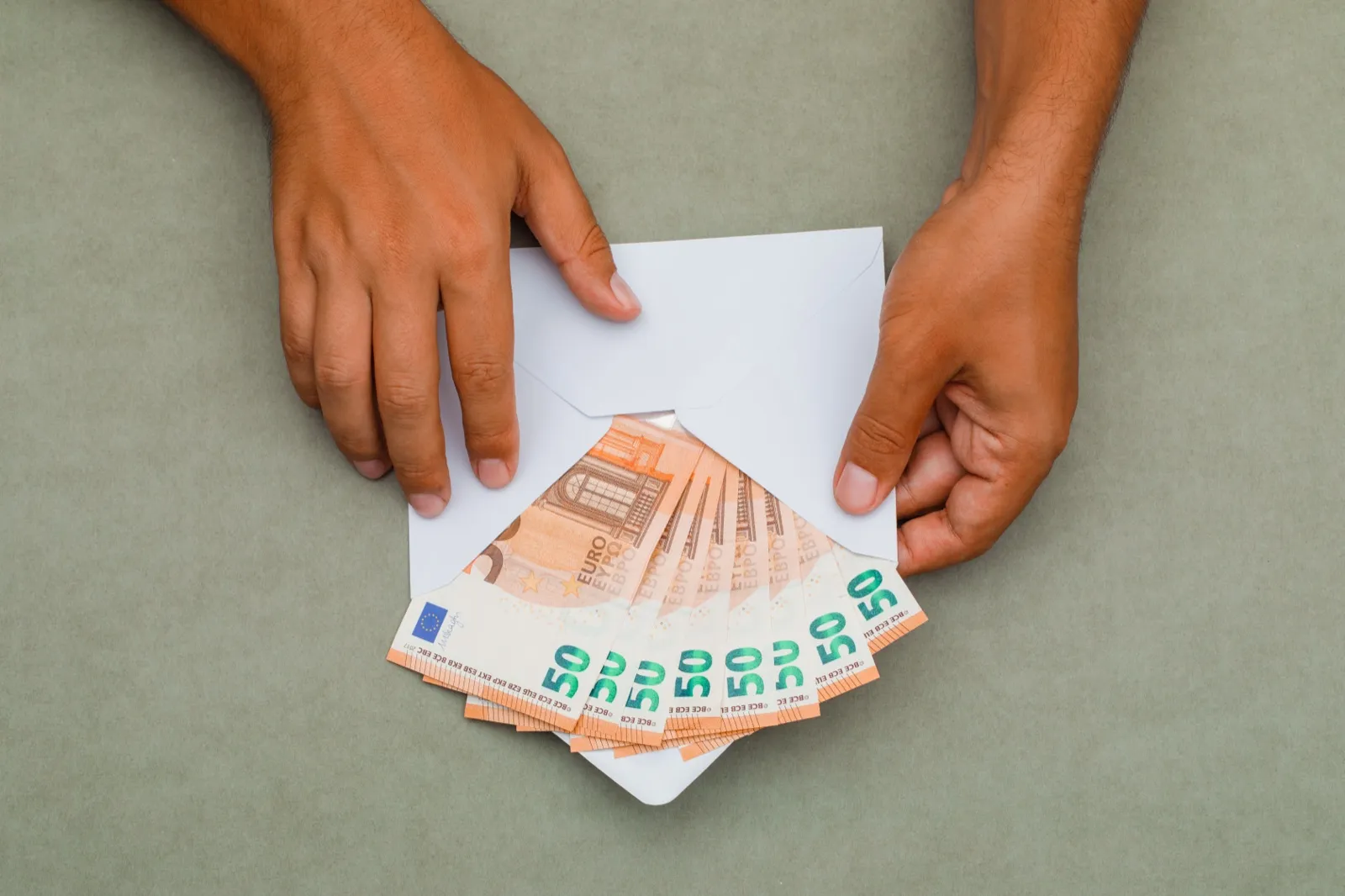 Mężczyzna wkłada banknoty euro do koperty - darowizna gotówkowa dla fundacji a próg 10 000 euro w ustawie AML